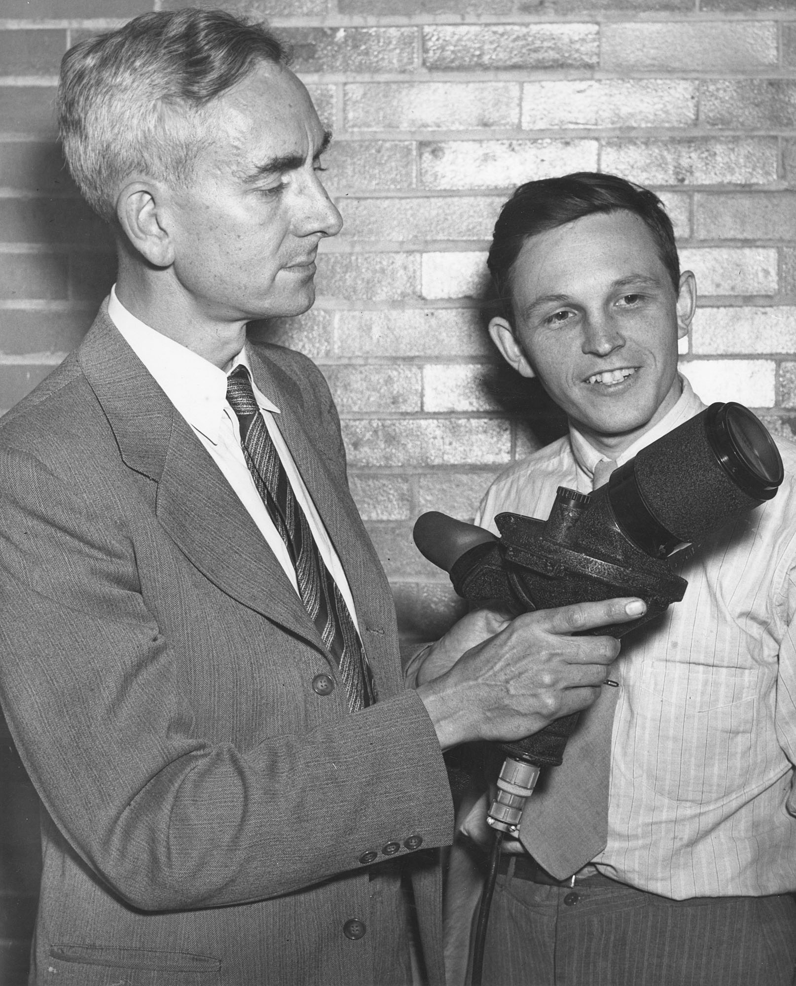 Institute of Optics Director Brian O’Brien (left) and Gordon Milne—a student at the time, later to become an Institute faculty member—looking at an Icaroscope, developed at the Institute. The device used phosphor to make the sun appear only 20 to 50 times brighter than the surrounding sky, compared to 10,000 times brighter to the naked eye. This helped antiaircraft gunners keep track of enemy planes diving with the full glare of the sun behind them. (University photo / Rare Books, Special Collections, and Preservation)