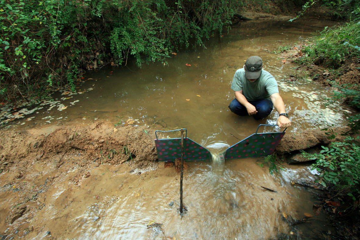 Pew Creek below Johnson Road, Lawrenceville, Ga. The metal structure is a small portable “V-notch” weir. A sediment dam was built on either side of it to force the water through the weir. Scientists can calculate gallons per minute flow in the stream by timing how long the flow going through the weir takes to fill a bucket.  Image from: https://www.usgs.gov/media/images/measuring-streamflow-through-weir, last accessed 4/18/17.