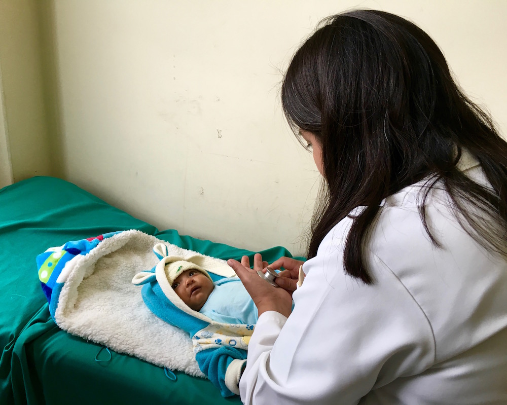 Dr. Patricia Borja, 37, has practiced medicine at the Subcentro de Salud in La Victoria for three years. Here, she examines a member of the new La Victoria generation, Cristofer Elián Chilrisa Sevilla, 2 months old, and he is healthy. Image by Caitlin Cotter. Ecuador, 2016.