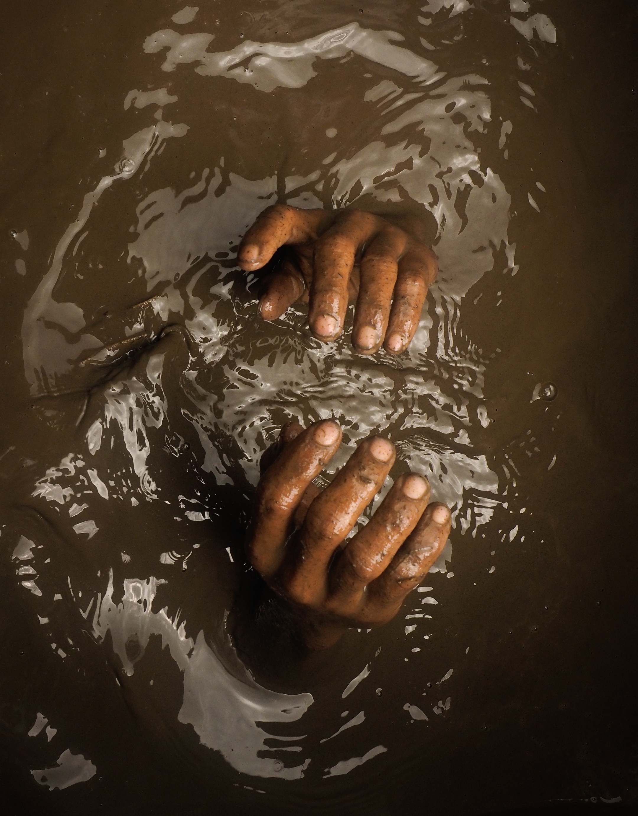 Here, a compressor miner sinks below the muddy water to begin another dive for ore that can last two or more hours. Image by Larry C. Price. Philippines, 2013.