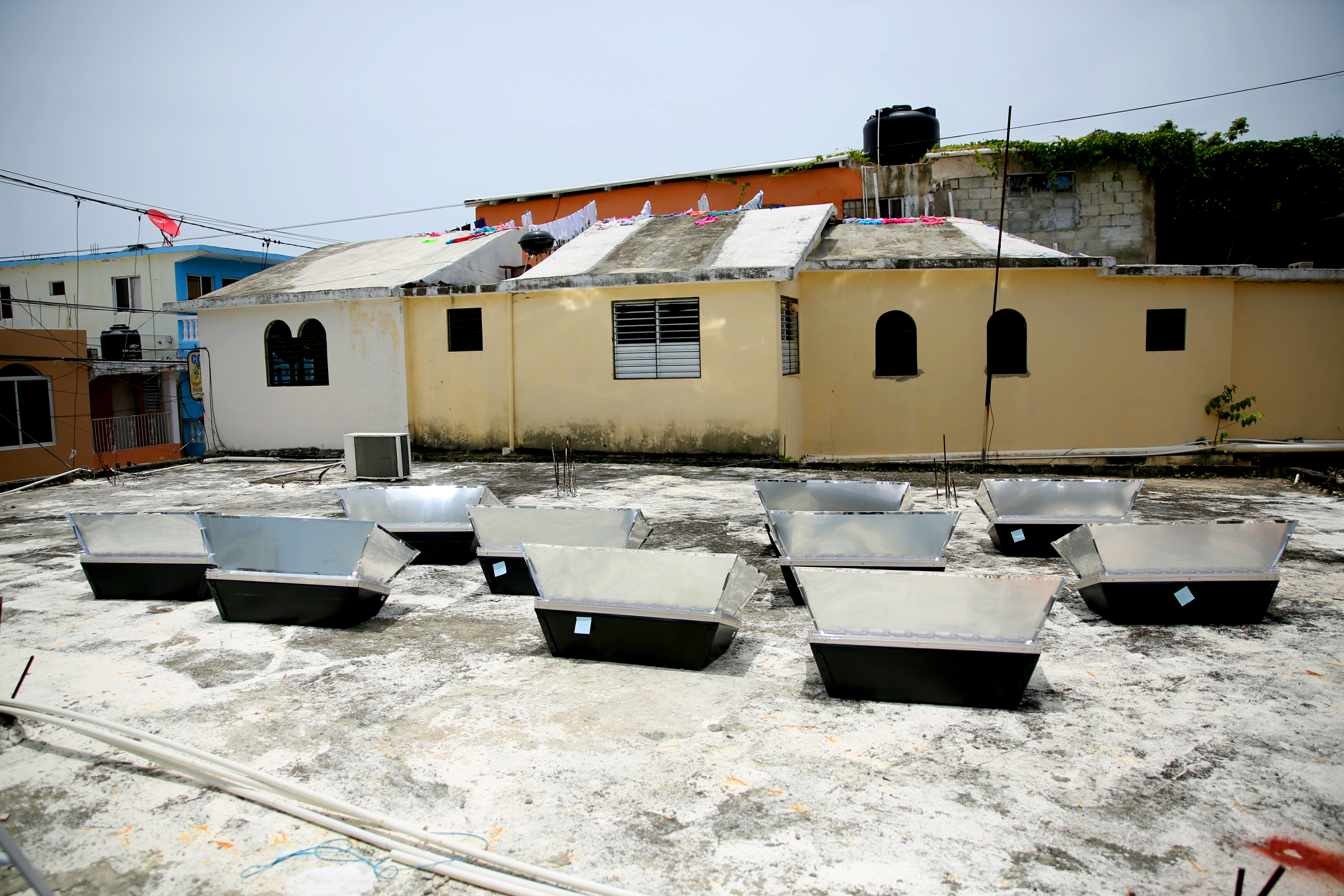 Ten solar ovens sit atop the Igelsia Evangelica Dominicana church roof in Sosua. Temperatures on the ovens need to reach more than 200 degrees Fahrenheit before cooking can start. Image by Makenzie Huber. Dominican Republic, 2016.