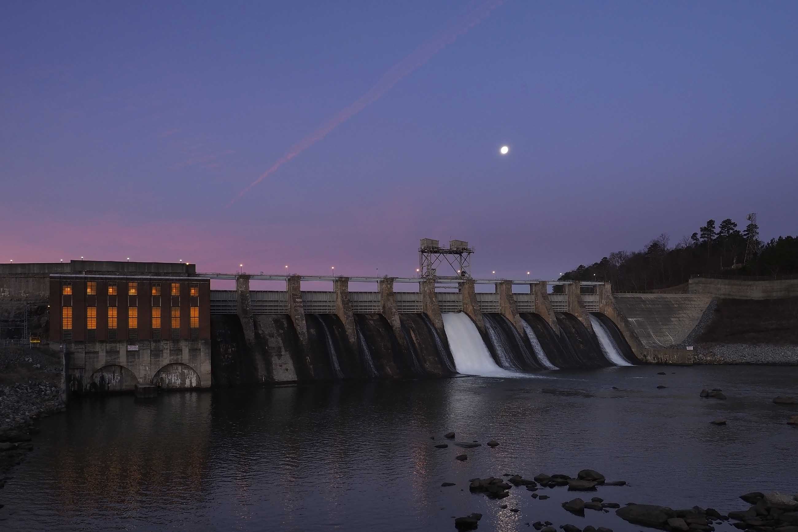 The moon set in the west as water from Lake Hickory on the Catawba River outside Conover, NC, flows through the gates of the Oxford Hydro Station dam. Image by Larry C. Price. United States, 2016.