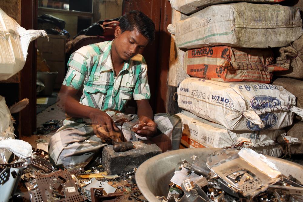 A villager in Sangrampur breaks down and sorts through various types of e-waste. Image by Sean Gallagher. India, 2013.