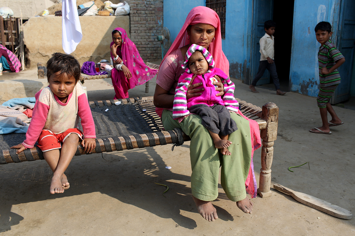Survana, 27, holds her youngest child Reetu, 2, who has suffered from spastic cerebral palsy since birth, outside their home in the village of Teejaruhela. She is one of many children in the village who suffer from development health issues. Image by Sean Gallagher. India, 2013.