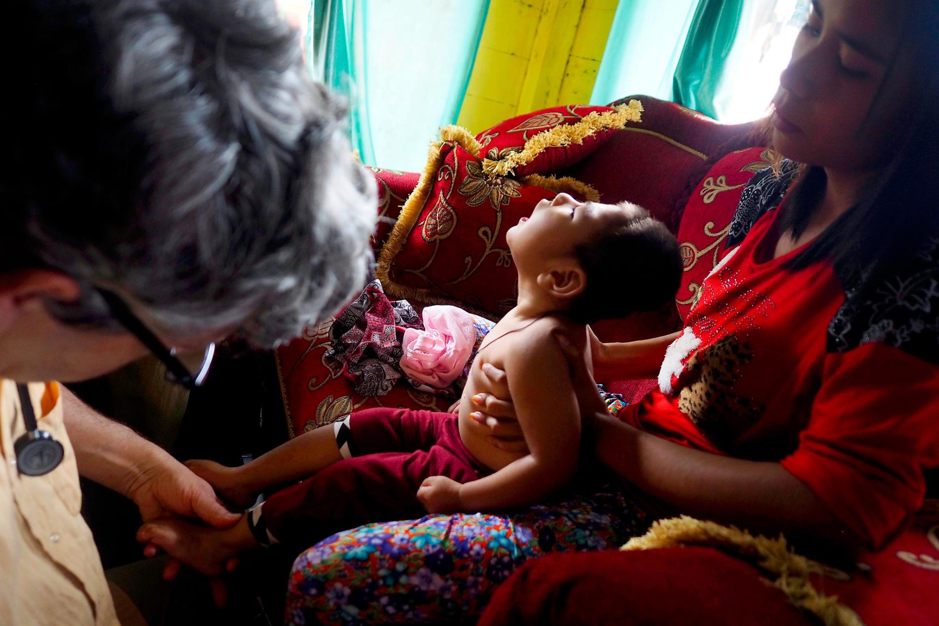 Stephan Bose-O’Reilly, a pediatrician and environmental health expert, examines two-year-old Rifky Aldiansyah, who lives in the village of Cisitu, for symptoms of mercury poisoning. Rifky was in good health until his third month when he began losing motor control. Rifky’s mother, right, who lived in Cisungsang, a nearby mining community, said her home there was surrounded by gold processing centers. Mercury poisoning is “a serious health problem” for children in Indonesia, Bose-O’Reilly says. Image by Larry Price. Indonesia, 2015.